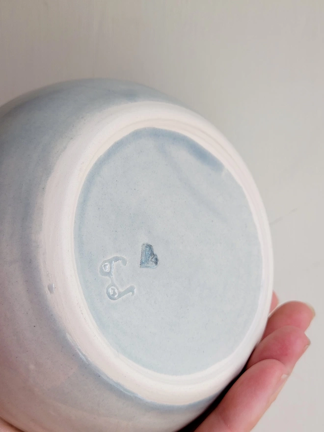the base of a grey ceramic cat feeder bowl showing a blue heart 