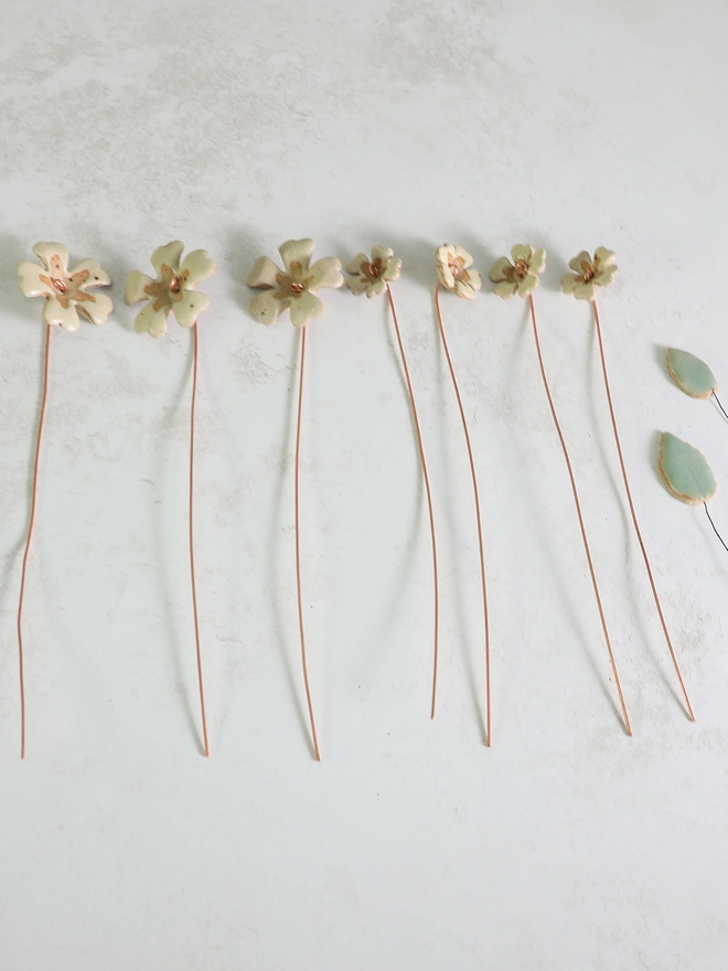 yellow ceramic primrose stems laying flat on a white marble surface