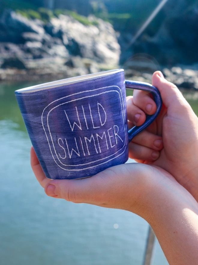 wild swimmer mug in front of the sea