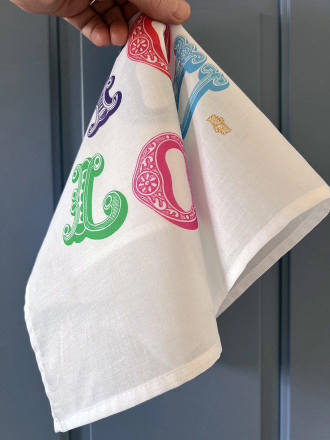 A Mr.PS Love You Lots Multicoloured Printed Handkerchief held by a white hand against a blue background