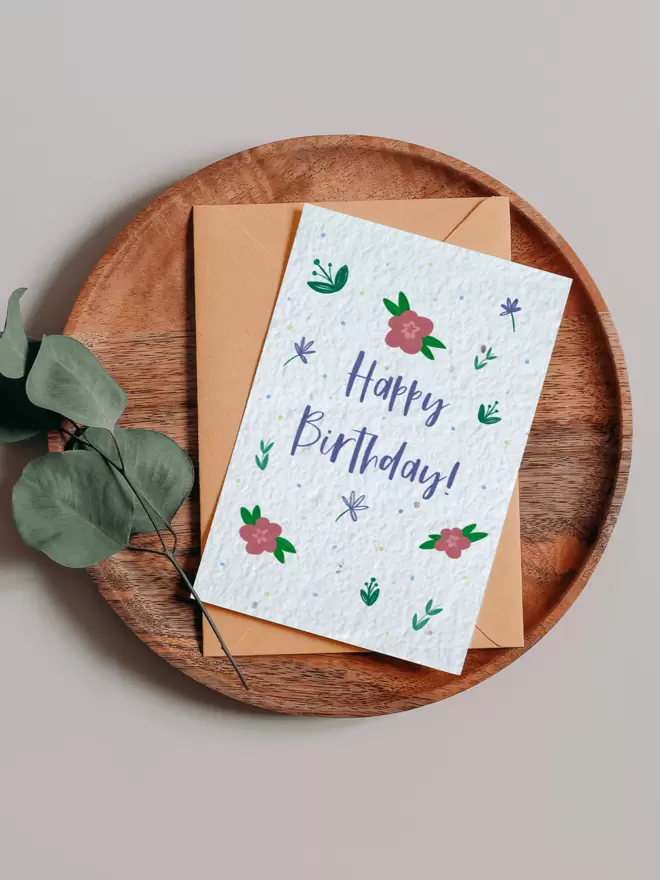 Happy Birthday Seeded Card with floral illustrations on a wooden tray next to a Eucalyptus branch