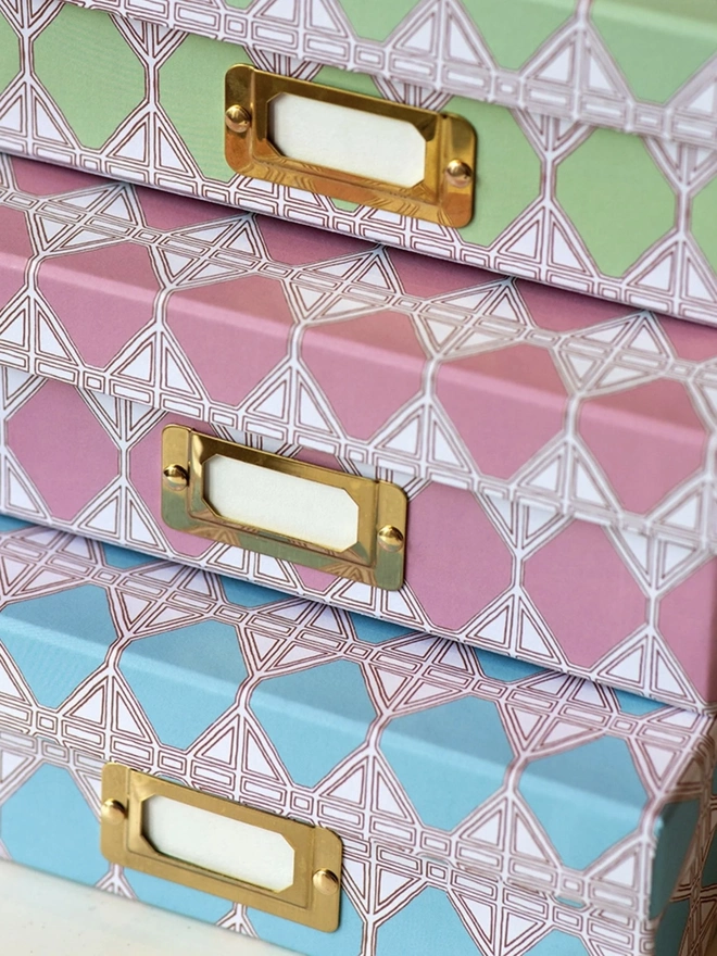 Tijan Lidded Portfolio Box, a collection of colourful portfolio boxes stacked on a plain surface. 