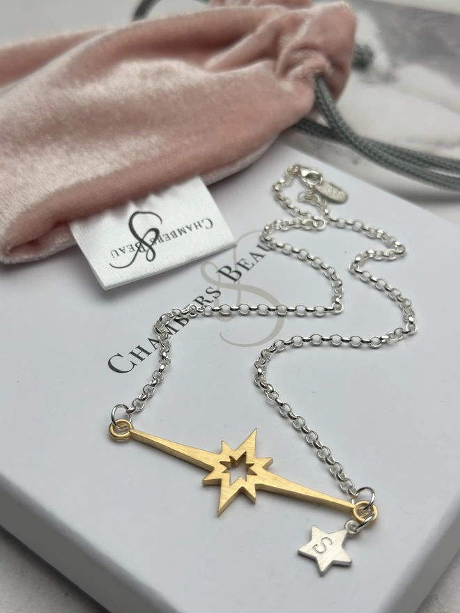 sterling silver chain with horizontal supernova star charm in gold, with a small personalised sterling silver star charm