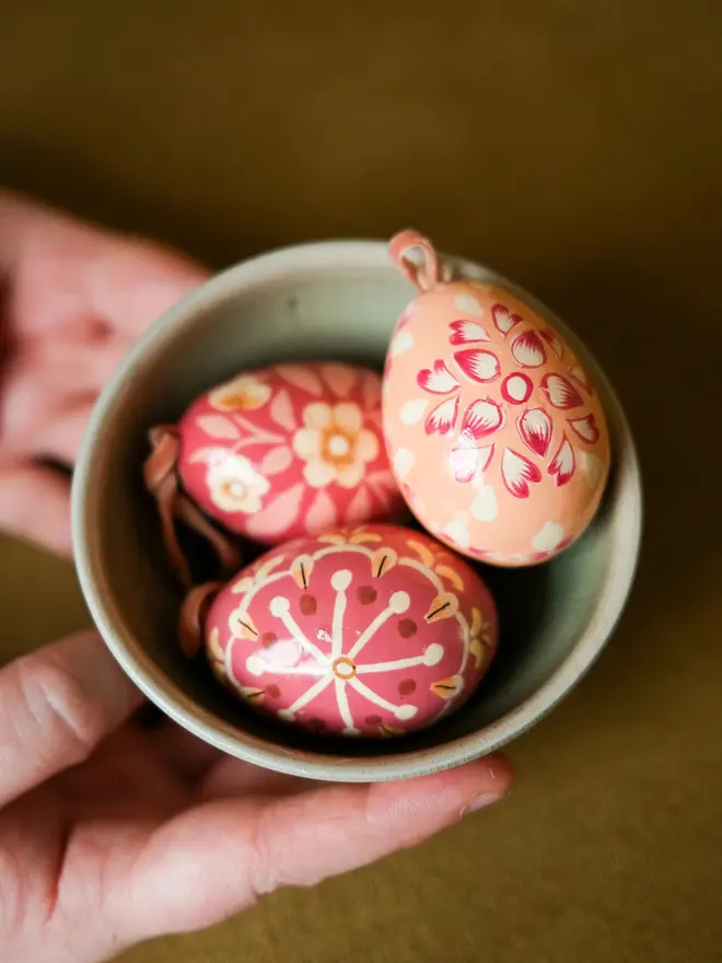Group shot of hand painted decorative eggs in a bowl on a wooden table
