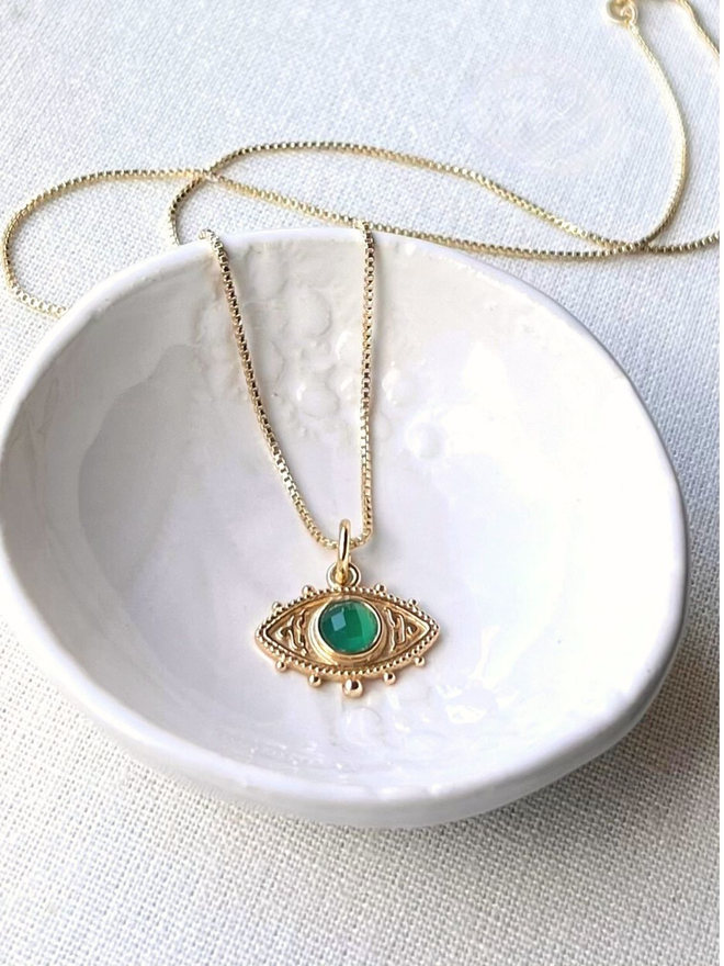 a gold evil eye charm necklace with a green quartz stone on a gold box chain necklace