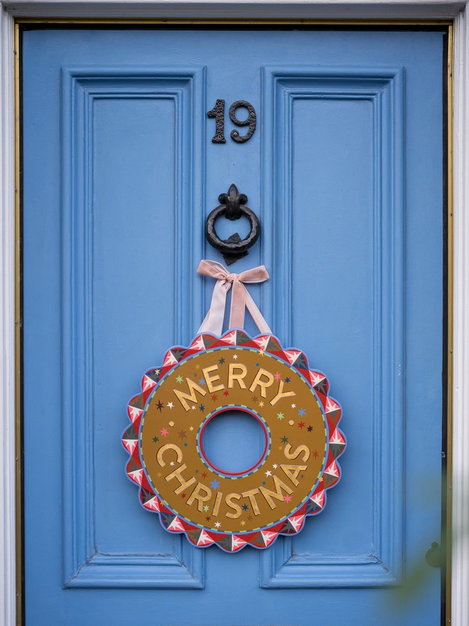 Multicoloured Hand painted Christmas Wreath with gold leaf lettering on a blue front door