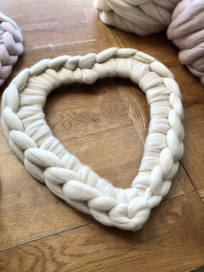 Light cream oyster merino woolly heart on an oak table