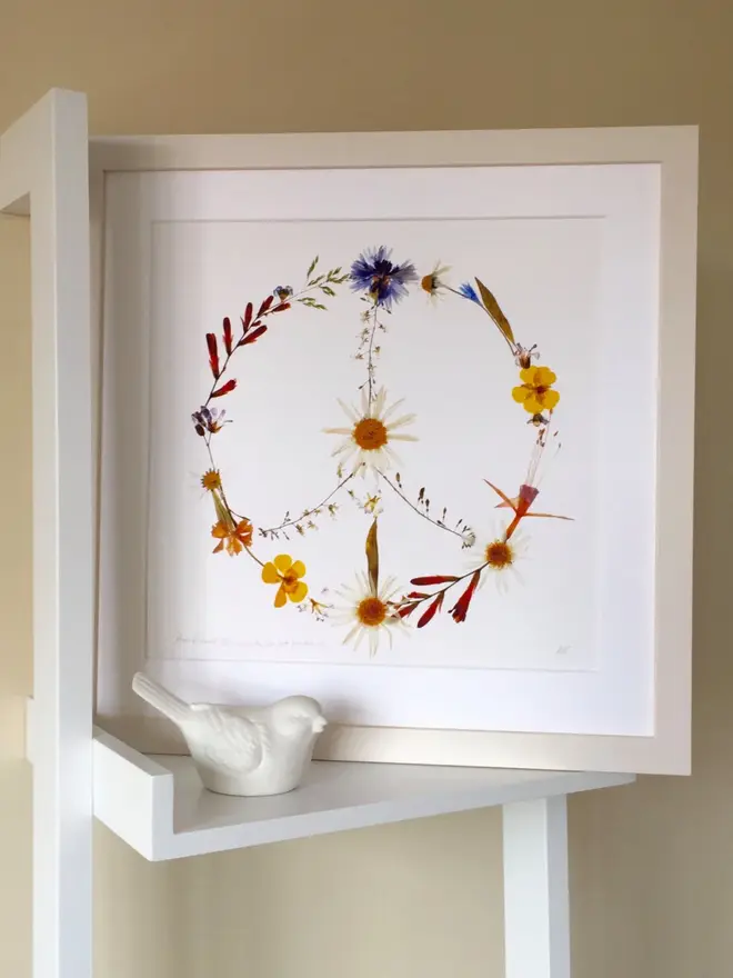 Pressed Wildflower Peace Sign Print, a wildflower peace sign print sitting framed against a stand. 