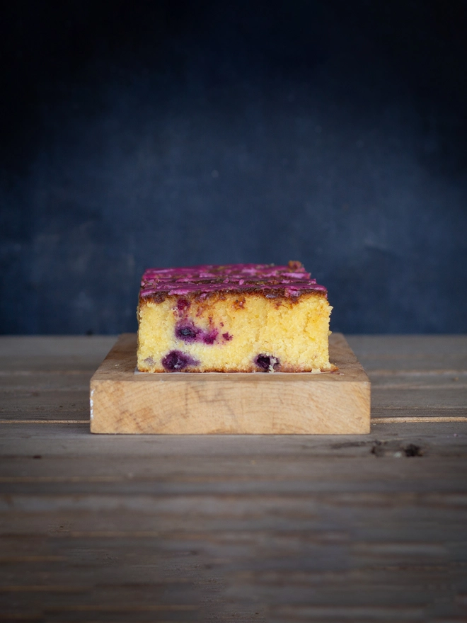 Lemon and Blueberry cake showing a light sponge with purple blueberries scattered in the middle