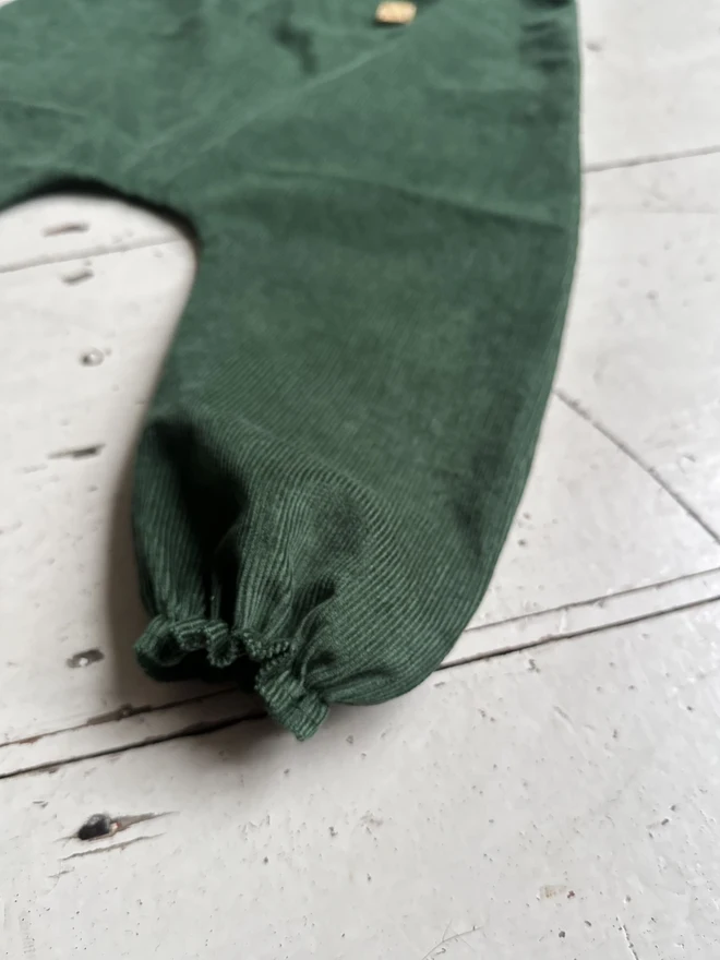 close up elastic hem of kids organic cotton needlecord dungarees dark green