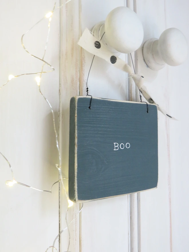 inky blue hand painted wooden sign with boo message and spotty ribbon detail