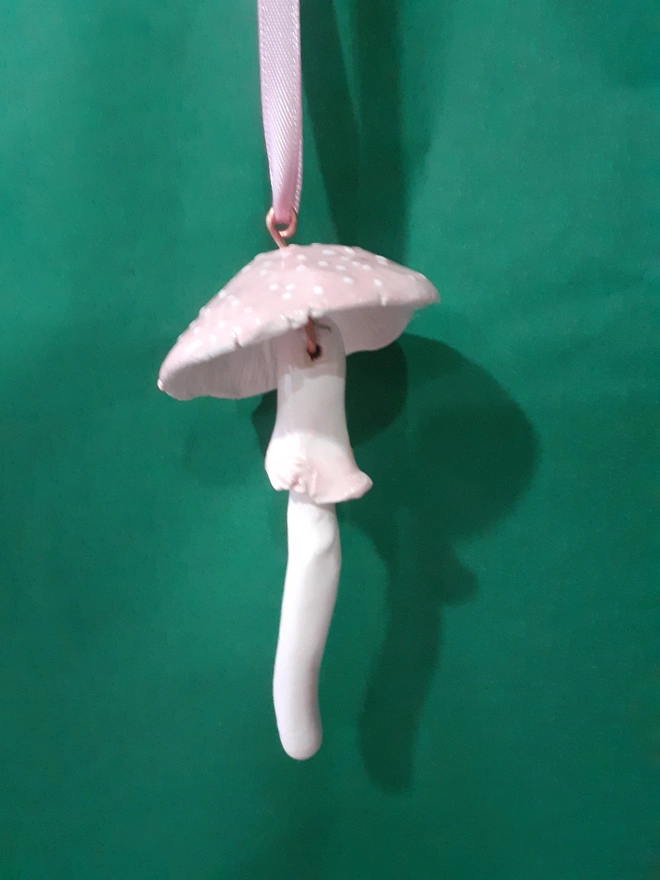 Handmade ceramic pink toadstool hanging decoration with white polka dots and a matching pink satin ribbon.
