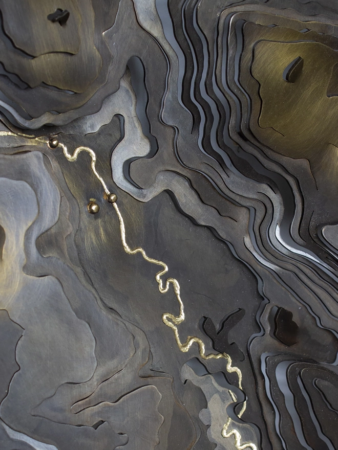 detail showing an engraved river on an antiqued map and golden location markers