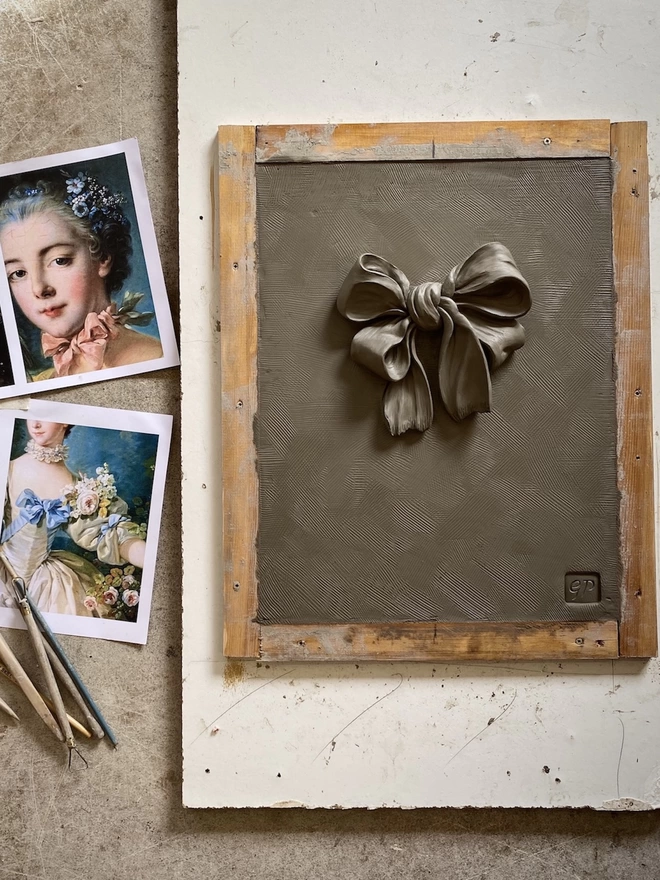 Clay model of Rococo Bow sculpture with modelling tools and inspiration images inc François Boucher painting