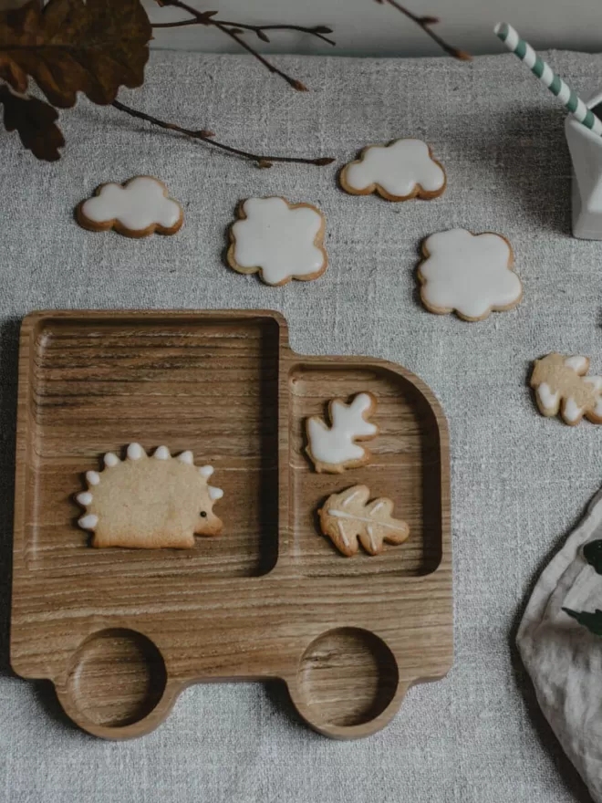 wooden lorry plate with hedgehog cookie, leaf cookies and cloud cookies surrounding