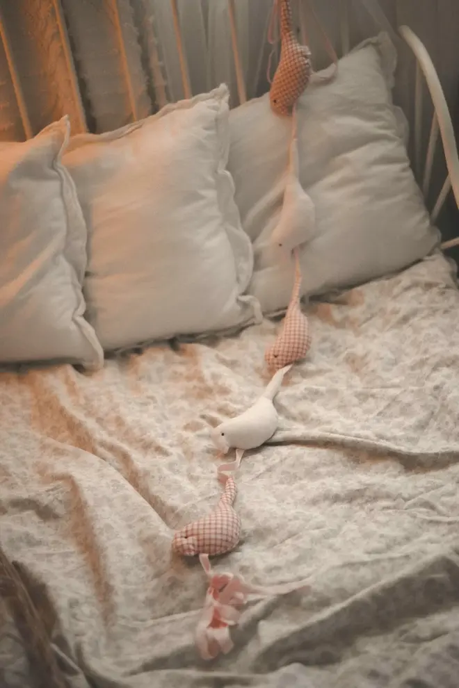Cotton Bird Garland Decoration, a red and white cotton bird garland sitting on a child's bed accompanied by other bedding accessories. 