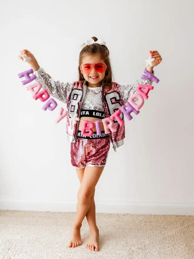 Girl holding a pink Happy Birthday banner