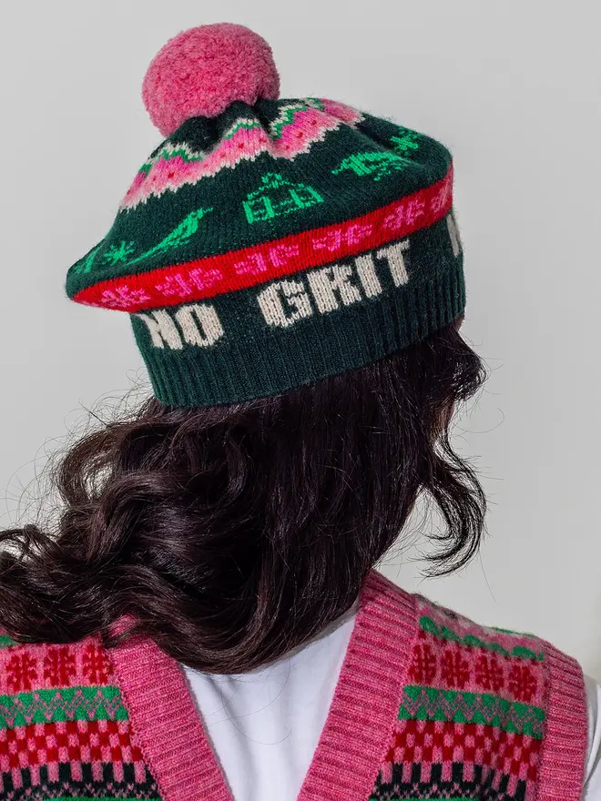 Model wearing the fairisle feminist beret in Forest green and bubblegum  featuring the wording No Grit No Pearl