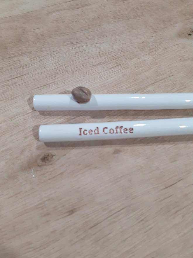 Eco-friendly handmade ceramic straw for iced coffee, reusable and dishwasher safe with lettering and raised coffee bean design