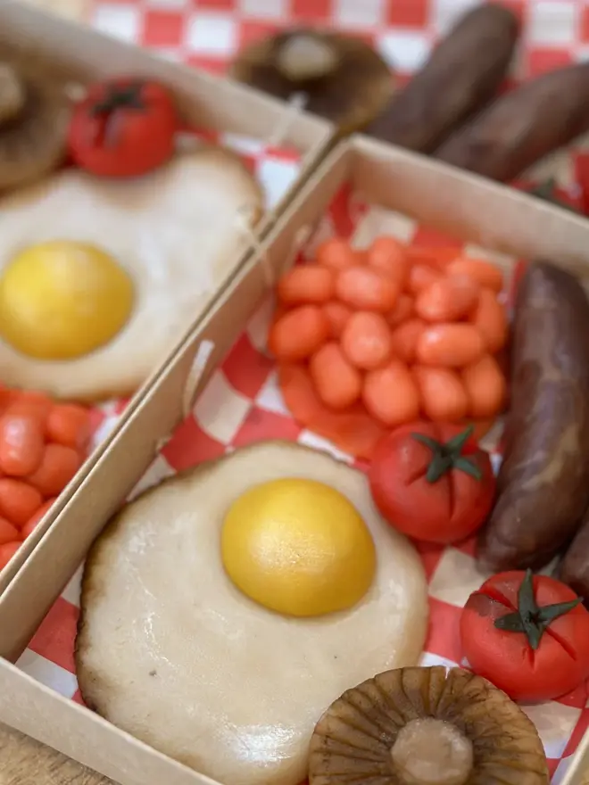 Brekkielicious Marzipan Box, sweet marzipan box displayed on a table surface. In the image are marzipan eggs, beans, mushrooms, tomatoes and sausages along with traditional red and white patterned cloth. 
