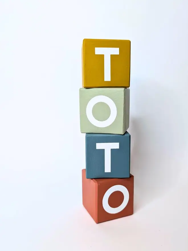 personalised hand-painted name blocks. the name 'toto' spelt in different coloured square blocks.