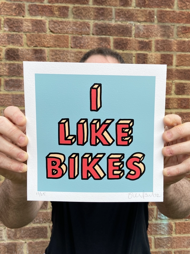 "I Like Bikes" Mini Hand Pulled Screen Print square blue background and the words i like bikes hand drawn then printed on top in red letters and a black outline 