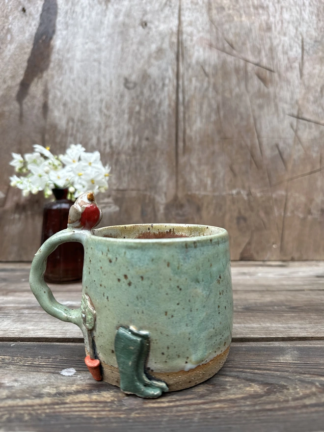 Robin perching on a green gardeners mug