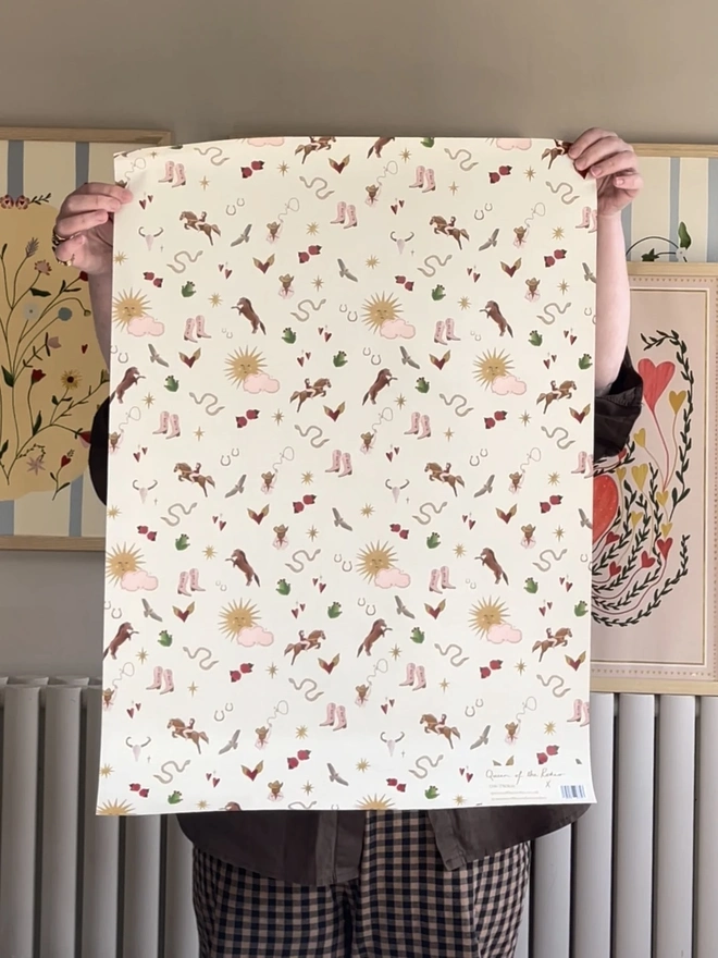 Wild Rodeo Gift Wrap (3 Sheets), a person holding up the wrapping paper indoors. 