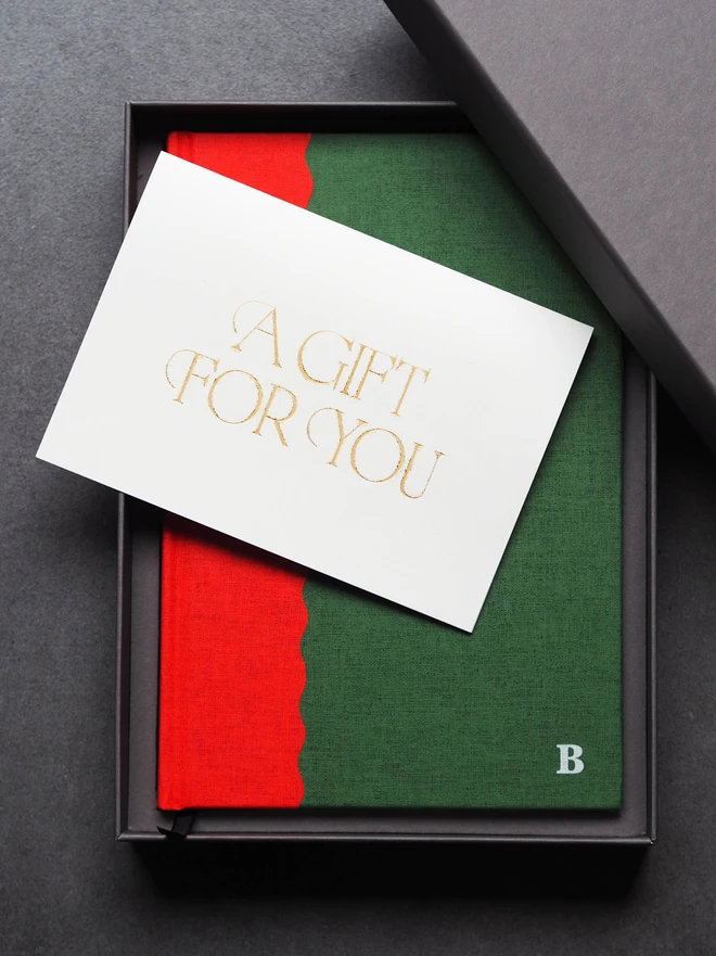 a red and green two tone hardcover journal in a gift box and with a gift card