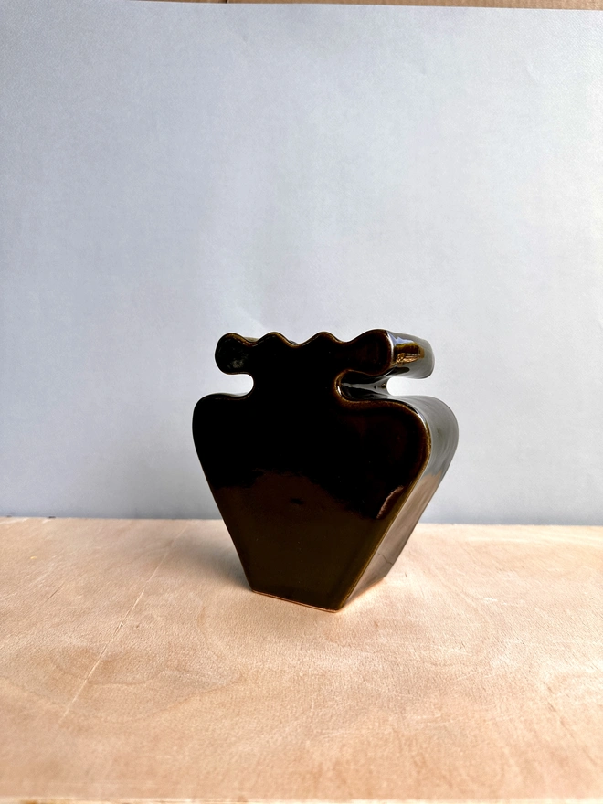A black vase with a blue backdrop.