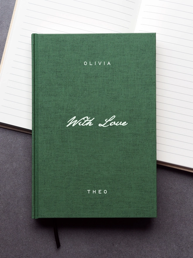 Personalised Hardcover With Love Notebook. A green linen hardcover journal with the words With Love written across the middle in a script font in white ink. The book is personalised with a name at the top and at the bottom of the book.