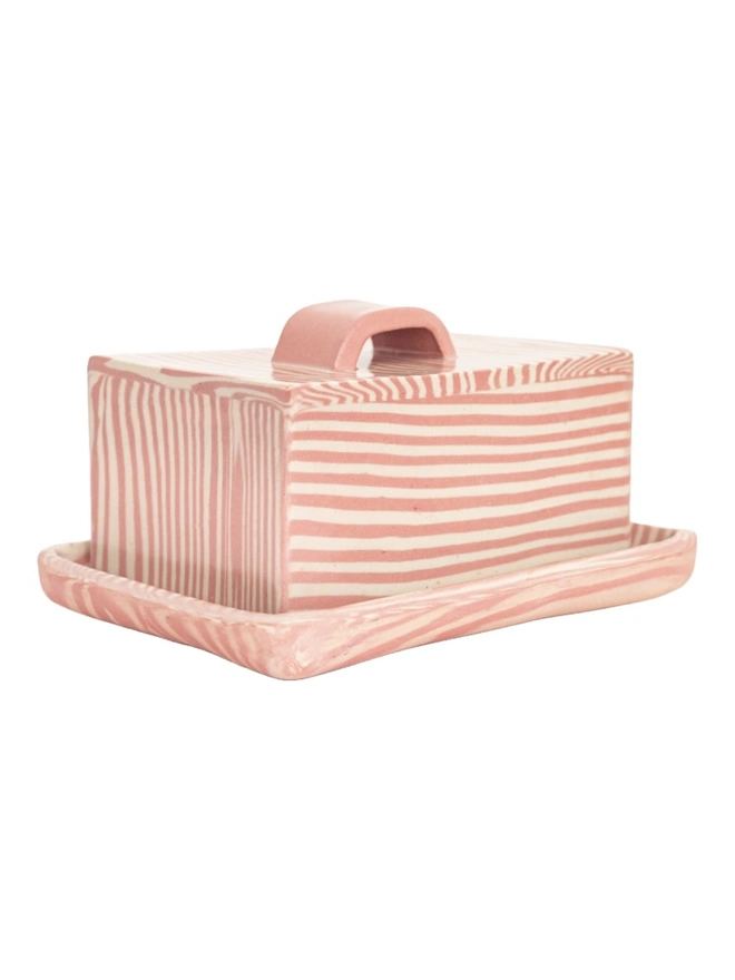 Striped Butter Dish, a colourful striped butter dish sitting on a white surface against a plain backdrop. 