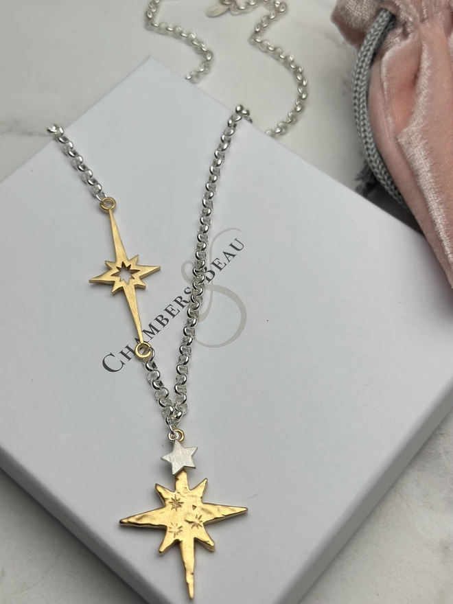 sterling silver chain with horizontal supernova star charm in gold, with a small personalised sterling silver star charm over a large textured north star charm