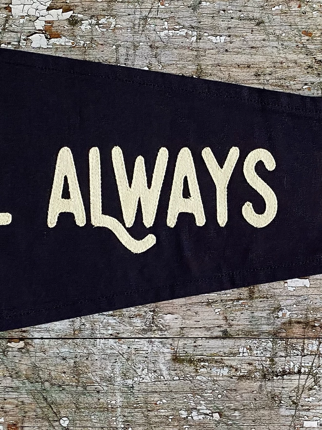 Detail of the navy 'It'll always be you' pennant flag. This shows the word always in ivory canvas.