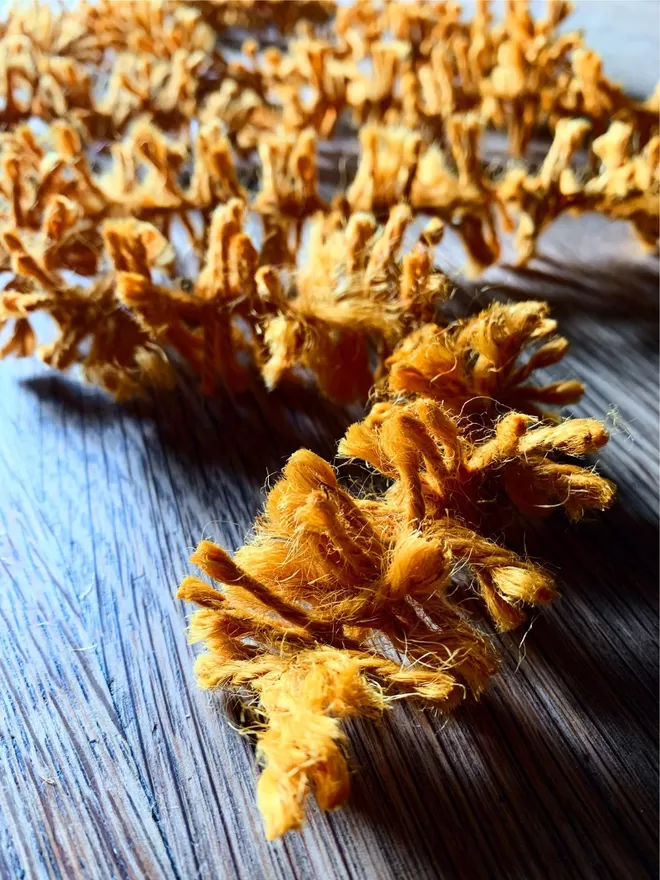 Close up of golden Warm Gold dyed jute string tinsel AKA Strinsel on an oak table