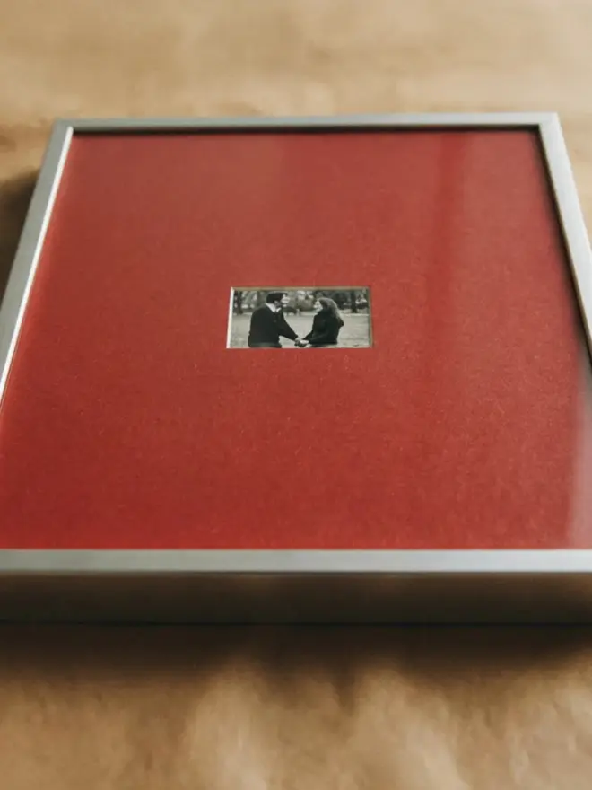 Vermillon Mounted Silver Picture Frame, displayed on a wooden table. 