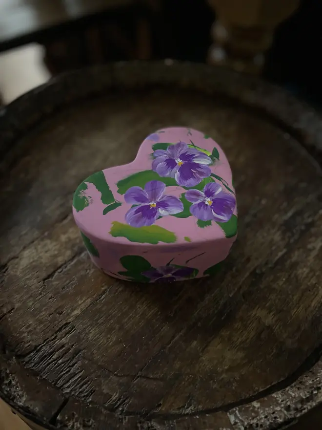  hand painted floral ceramic heart shaped keepsake box background in a pale pink with purple pansy flowers