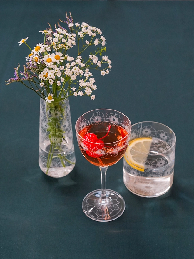 Floral Twist crystal bud vase holding colourful wildflower arrangements placed on a dark green tablecloth.