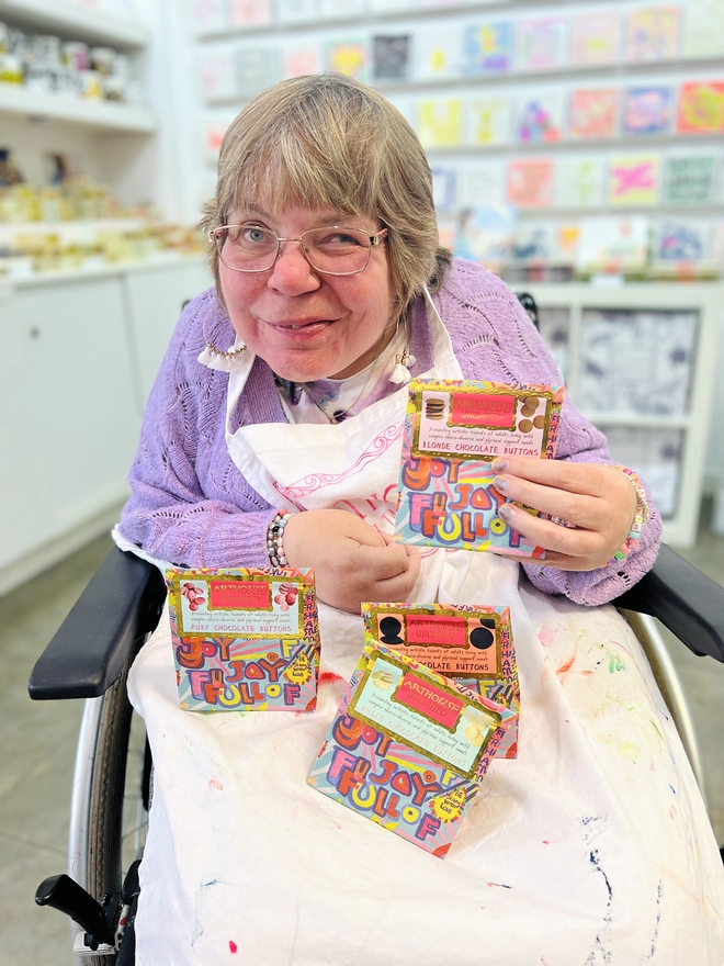 Happy artist holding bright colour bag of full of joy charity dark chocolate buttons perfect gift