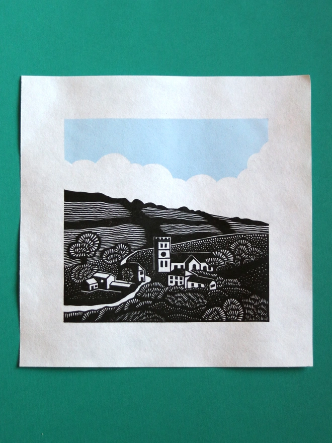 Original handmade linocut print featuring a Cornish village with a church, houses, fields and trees
