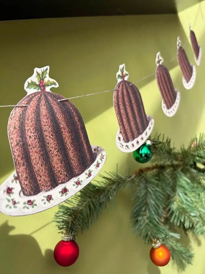 A set of nine paper cut out Christmas puddings strung as bunting