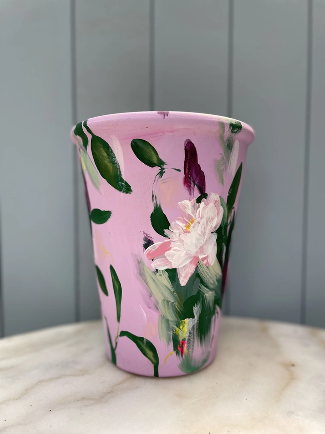 Unique hand-painted terracotta pot featuring pink peony flowers on a pale pink background