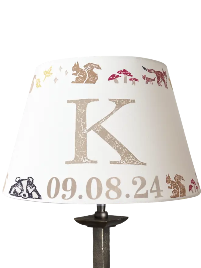 Personalised kids lampshade with woodland animals and the letter K and date, handmade empire lampshade in neutral tones. Empire light shade for kids bedroom design, featuring woodland animals, perfect as kids lighting or presents for new parents.