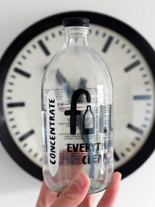 concentrate bottle being held in front of a clock