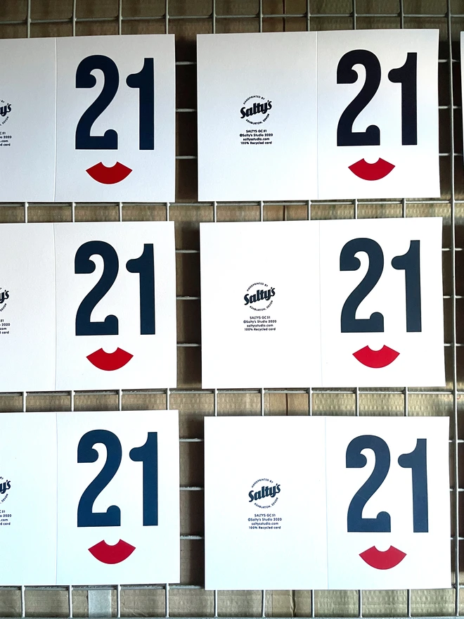 Six unfolded screen printed 21 birthday cards. On a drying rack.