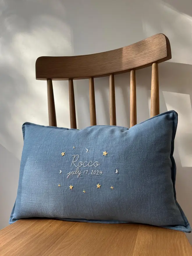 Personalised Handmade Embroidered Linen Cushion, blue personalised cushion with name on chair. 