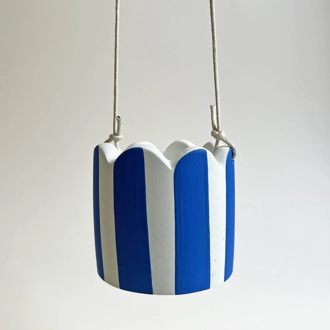 Blue and white scalloped hanging jesmonite pot against a pale background.