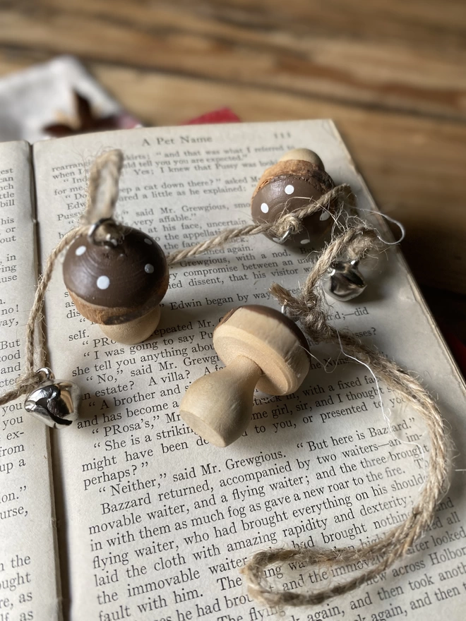 A string of Hand Painted Wooden Toadstool Bell Garland trailing across a page of a book
