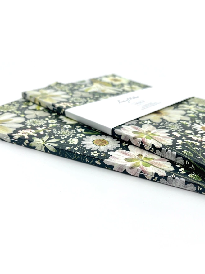 Pretty ruled Notebook with cover design created from pressed white flowers on a black background.