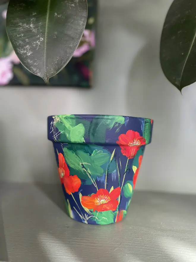 hand painted terracotta floral plant pot rich dark blue background with red orange Icelandic poppy flowers 